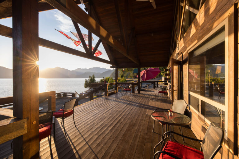 A cedar deck overlooks a view of the water and mountainous islands in the background.